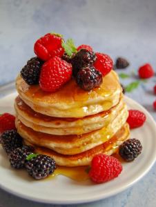 Fluffy American pancakes with berries and syrup