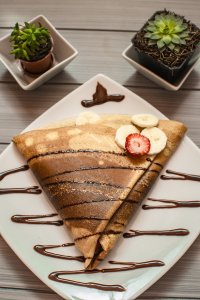 Folded crepe with chocolate sauce, banana and strawberry.